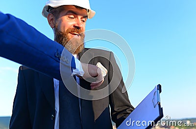 Construction and bribery concept. Hand puts money into coworkers pocket Stock Photo