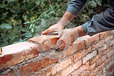 Construction bricklayer worker building with bricks, mortar, trowel. Industrial construction site details Stock Photo