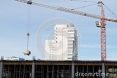 A construction crane is transporting a tool. Boom crane on the construction of a high-rise building. The crane hook with slings Stock Photo