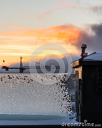 Sunrise with clouds and construction cranes with frosty ice crystals on glass pane Stock Photo