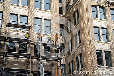Construction crew on scaffolding repairing outside of building Editorial Stock Photo