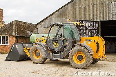 Construction digger loader in farm yard with barn Editorial Stock Photo