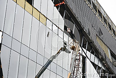 Construction, facade work. A construction crane is working. Glass and concrete Stock Photo