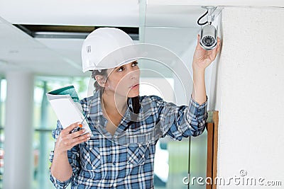 Construction female worker with ladder checking cctv installation Stock Photo