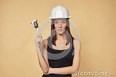 Construction girl in a white hard hat and protective construction mask holding a caliper. makes the measurement of the smile Stock Photo