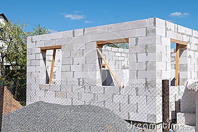 Construction of a house from gas silicate white blocks. A mountain of gravel near an unworthy house Stock Photo