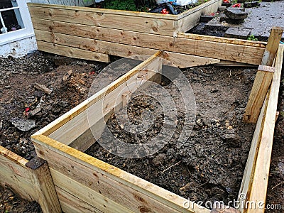 Construction if a small residential retaining wall and planter bed from timber material Stock Photo