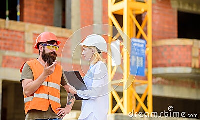 Construction industry concept. Discuss progress project. Woman engineer and bearded brutal builder discuss construction Stock Photo