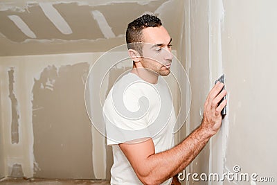 Construction industry worker with tools plastering walls and renovating house in construction site Stock Photo