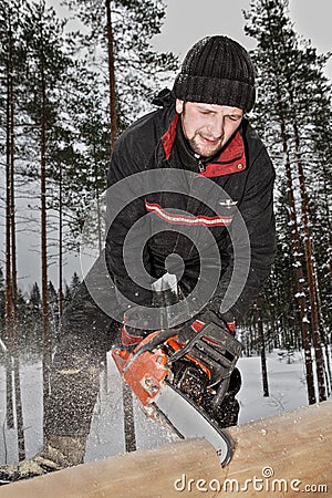 Construction of log house, a young worker sawed timber, using a Editorial Stock Photo