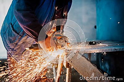 Construction male worker using electrical angle grinder for cutting iron bars Stock Photo