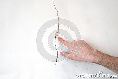 Construction man worker repairing a crack wall of a home, plastering cement on wall. Builder applying white cement to a Stock Photo