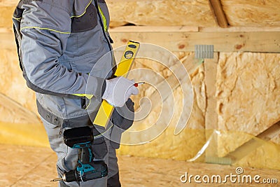 Construction mason worker with building level and screwdriver on attic with environmentally friendly Stock Photo