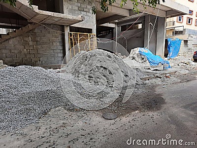 Construction materials like Artificial Sand or crushed sand, small stones, cement heap on roadside during construction of building Stock Photo