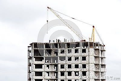 The construction of a multi-storey building of brick and concrete. Fragment of a modern house and a construction crane. Close-up Stock Photo