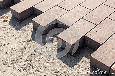 Construction of a new pavement of paving slabs closeup detail. Pavement cobblestone blocks construction of path, road or sidewalk. Stock Photo