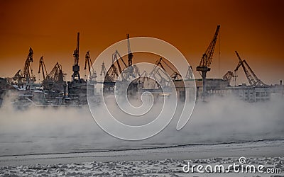 The construction of nuclear icebreakers at magic sunset, cranes of of the Baltic shipyard in a frosty winter day, steam Stock Photo