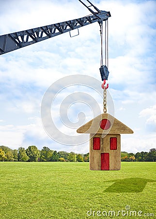 The construction of a prefabricated building - concept image with a tower crane holding a wooden house Stock Photo