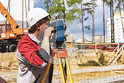 Construction of a residential area. Geodetic stakeout. Surveyor at a large construction site. A man with a tachometer during work Stock Photo