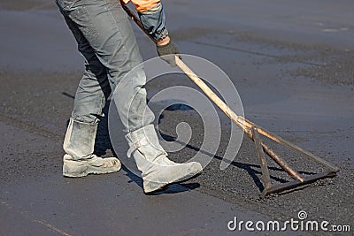 Construction road worker levelling fresh asphalt concrete Stock Photo