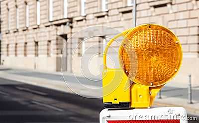Construction safety. Street barricade with warning signal lamp on a road, blur building background Stock Photo