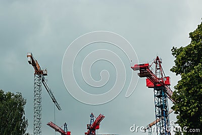 Construction site. Big industrial tower cranes with unfinished high raised buildings and blue sky in background. Scaffold. Modern Stock Photo