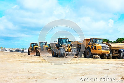 Construction site with bulldozers work trucks concrete pipes on cleared land on beautiful blue sky white clouds day Stock Photo