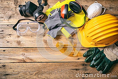 Construction safety. Protective hard hat, headphones, gloves and glasses on wooden background, copy space, top view Stock Photo