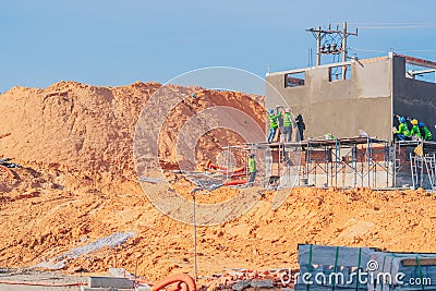 Construction site, steel concrete cement prefabricated house iron rebar, group many team builders doing exterior decor Editorial Stock Photo