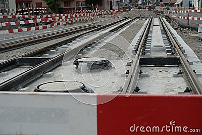 Construction site of a street-car line, embedding of metal rails in a concrete base with a barrier planks for security. Stock Photo