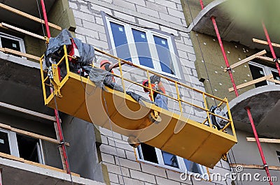 Construction suspended cradle with workers on a newly built high-rise building Stock Photo