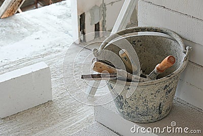 construction tool in old can at house site. prepare equipment for install wall white brick. put on cement floor Stock Photo