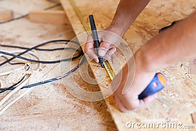 Construction work. Woodwork. Male builder marking point on hardboard. Stock Photo