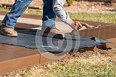 Construction Worker Applying Pressure to Texture Template On Wet Cement Stock Photo