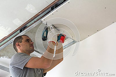 Construction worker assemble a suspended ceiling with drywall an Stock Photo