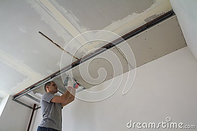 Construction worker assemble a suspended ceiling with drywall an Stock Photo