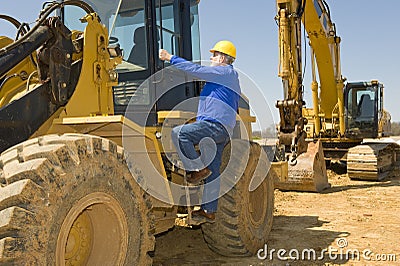 Construction Worker Climbing Heavy Equipment Stock Photo