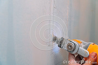 Construction worker cutting gypsum plasterboard by using electric cutter angle grinder Stock Photo