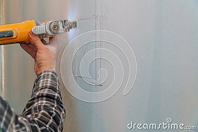 Construction worker cutting gypsum plasterboard by using electric cutter angle grinder Stock Photo