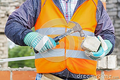 Construction worker divides brick with hammer Stock Photo