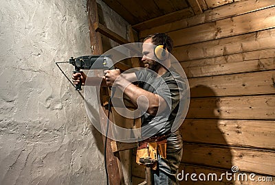 Construction worker drill perforate concrete wall Stock Photo