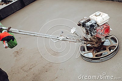 Construction worker finishing concrete screed with power trowel machine. Helicopter power tool and industrial tools Stock Photo