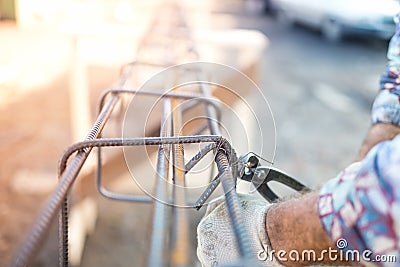 Construction worker hands securing steel bars with wire rod for reinforcement of concrete Stock Photo