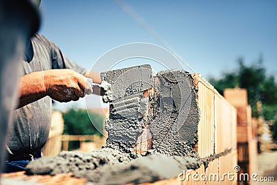 Construction worker installing brick masonry on exterior wall with trowel putty knife Stock Photo