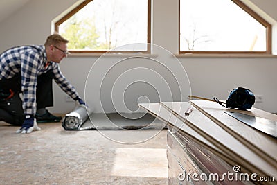 Construction worker installing laminate floor in a new renovated attic. Home improvement concept Stock Photo