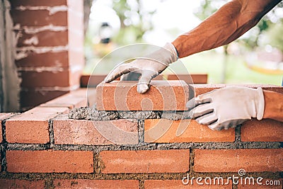 construction worker laying bricks and building barbecue in industrial site. Detail of hand adjusting bricks Stock Photo