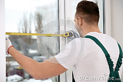 Construction worker measuring plastic window. Professional installation Stock Photo