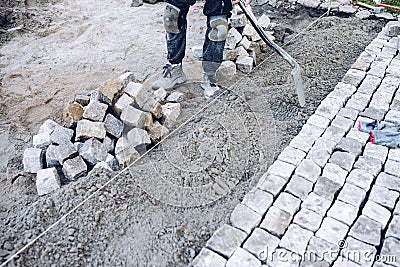 Construction worker placing stone tiles for pavement, terrace. W Stock Photo