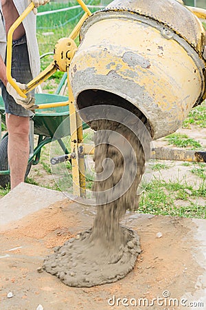 Construction worker poors concrete out of concrete mixer. process of creating cement on the construction site Stock Photo