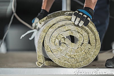 Construction Worker Preparing Roll of Mineral Wool Insulation Stock Photo